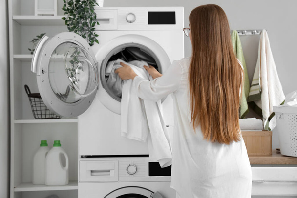 洗濯室に汚れた服を洗濯機に入れる女性 - 写真・画像