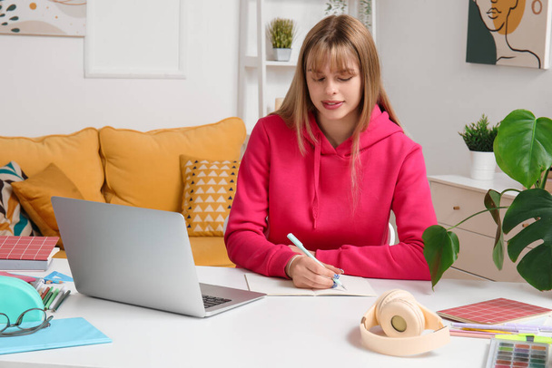 Женщина-студентка с ноутбуком делает уроки дома - Фото, изображение