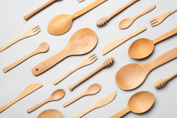 Cucharas de madera con tenedores y cuchillos sobre fondo gris - Foto, Imagen