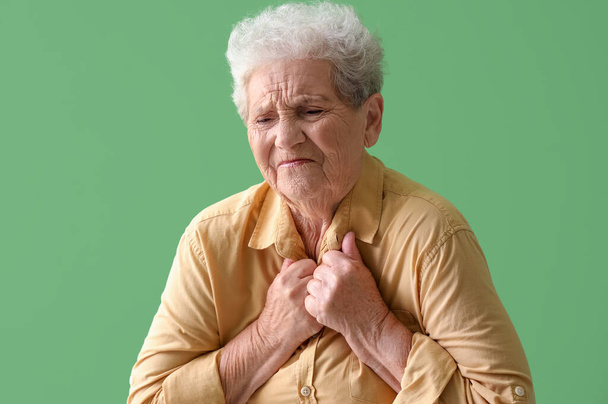 Mulher idosa tendo ataque cardíaco em fundo verde - Foto, Imagem