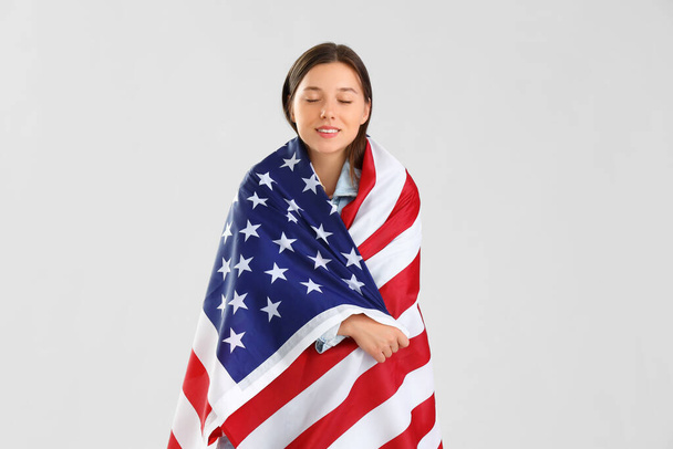 Mooie jonge vrouw met USA vlag op lichte achtergrond - Foto, afbeelding