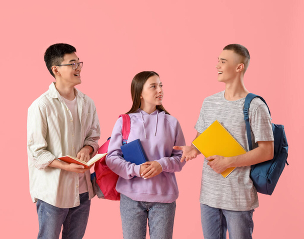 Счастливые студенты с рюкзаками и блокнотами на розовом фоне - Фото, изображение