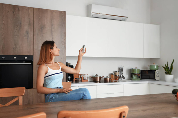 Nuori nainen kytkemällä ilmastointilaite keittiössä - Valokuva, kuva