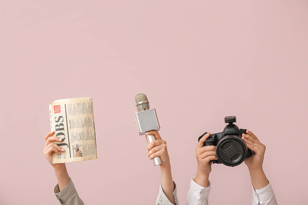 Kobiece ręce z gazetą, mikrofonem i aparatem fotograficznym na kolorowym tle - Zdjęcie, obraz