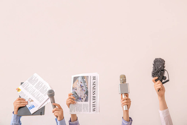 Vrouwelijke handen met kranten en microfoons op lichte achtergrond - Foto, afbeelding