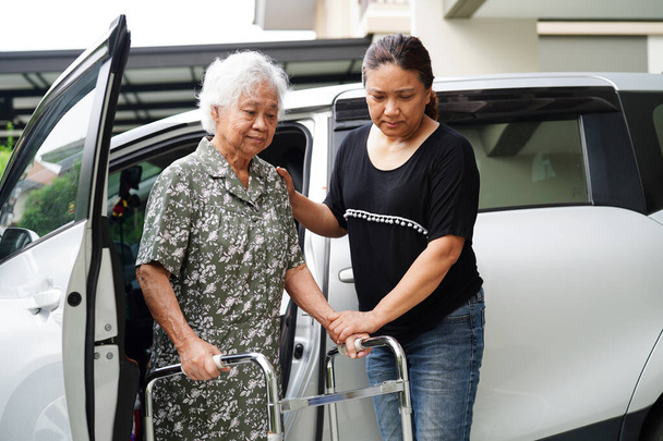 Pfleger helfen asiatischen älteren Behinderten, in ihr Auto zu steigen, medizinisches Konzept. - Foto, Bild