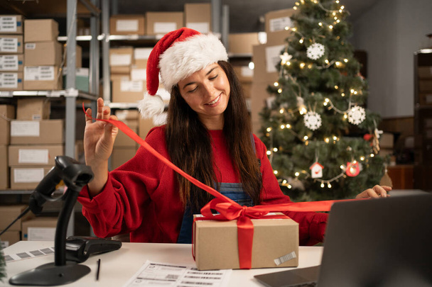 Business start up SME concept Young aspiring entrepreneur, small business owner, packing goods, preparing for shipment. Wearing a santa claus hat is a good income during the Christmas season sale - Photo, Image