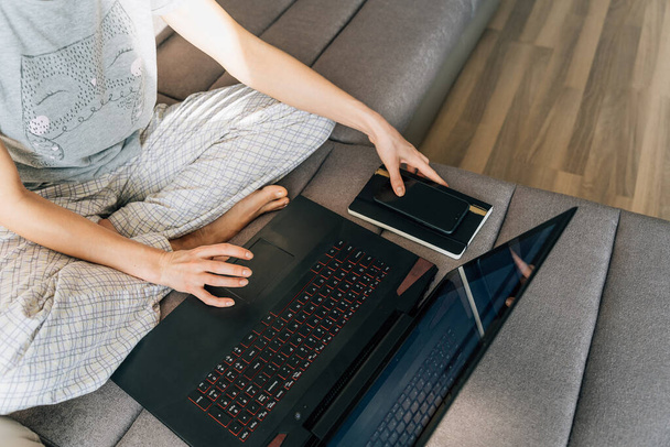 Una mujer en la ropa de casa utiliza un ordenador portátil. - Foto, imagen