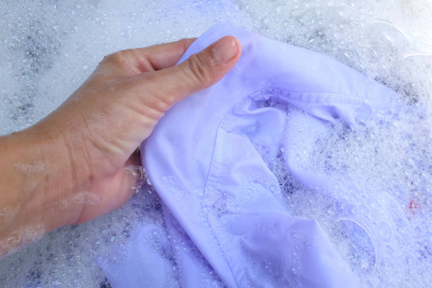 Рука азіатської домогосподарки, що миє білий одяг, шкільна форма, уніформа студента з бульбашковим миючим засобом у басейні. - Фото, зображення
