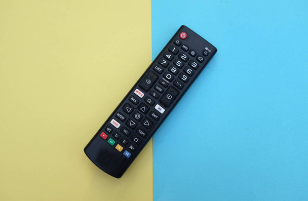remote control tv isolate on two tone yellow blue paper color for background.concept of watching tv.top view with place for text. - Photo, Image