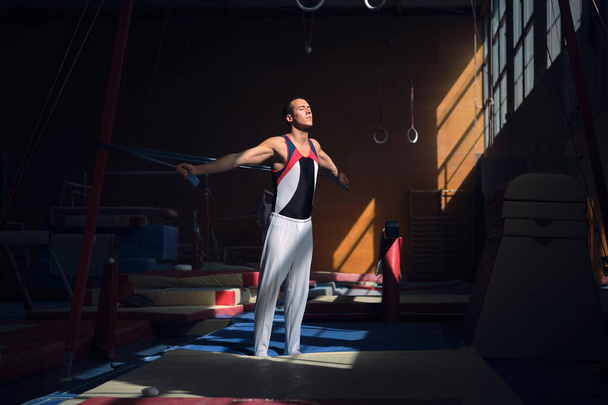 Νεαρή αθλήτρια γυμναστικής που τεντώνεται με λαστιχάκι στο γυμναστήριο πριν κάνει τις ασκήσεις της. - Φωτογραφία, εικόνα