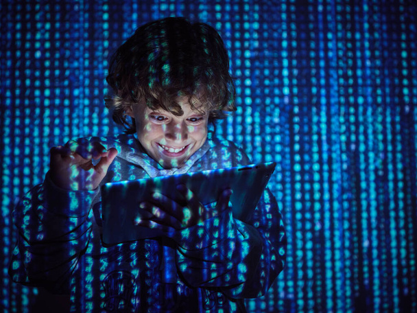 Gülümseyen, sırıtan, gri kapüşonlu hacker çocuk mavi kod sembolleriyle tableti tıklatıyor. - Fotoğraf, Görsel