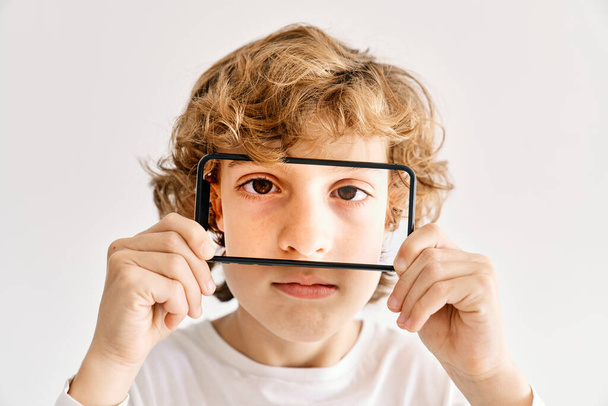 Kind posiert mit Handy und Fotos aus Teilen seines Gesichts - Foto, Bild