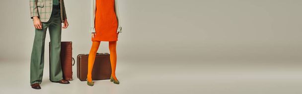 обрізаний вид на ретро-пара в помаранчевій сукні та блейзер біля старовинних валіз на сірому, банер - Фото, зображення