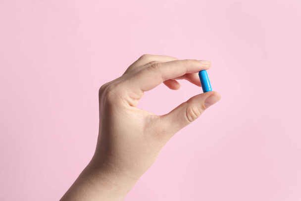 Woman holding pill on pink background, closeup - Foto, imagen