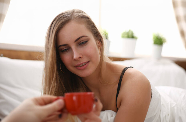 Любимый муж приносит ранний утренний кофе в постель для молодой красивой блондинки выпить чашку чая кофе рано утром в постели
 - Фото, изображение