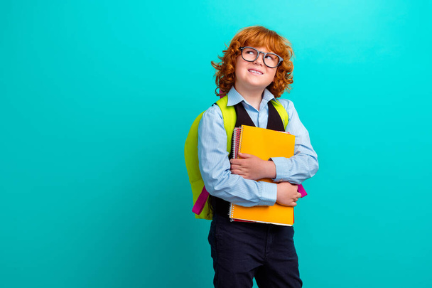 Portrait of creative minded little boy carry backpack hold copybook notebook look empty space isolated on turquoise color background. - Foto, Imagem
