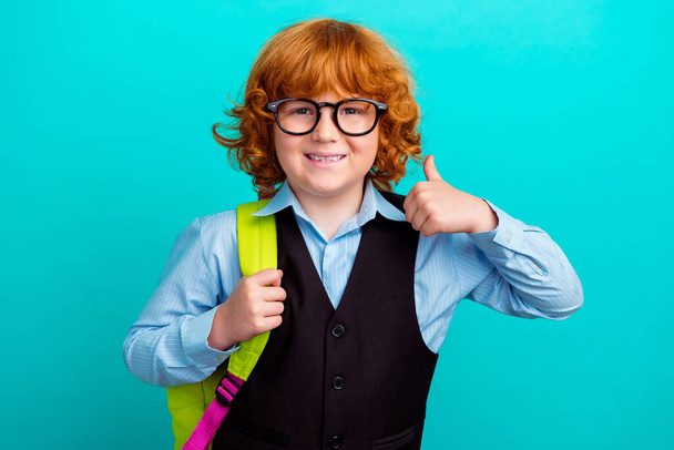 Ritratto di amichevole intelligente ragazzino sorridente portare zaino dimostrare pollice su isolato su sfondo acquamarina colore. - Foto, immagini