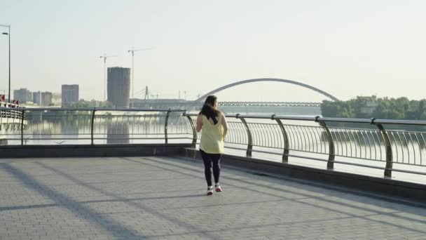 Кавказька спортивна дівчина закінчує ранковий біг у міському пейзажі. Жінку катують і співають після бігу на вулицях міста, міського спорту. Високоякісні 4k кадри - Кадри, відео