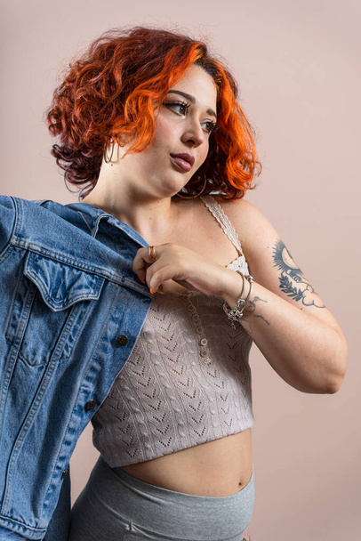 Μοντέρνο τατουάζ μη δυαδικό κορίτσι κοκκινομάλλα βάζοντας στο σακάκι της. - Φωτογραφία, εικόνα