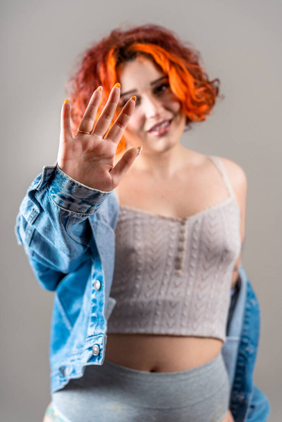 Chica pelirroja no binaria tatuada moderna con la mano levantada en señal de stop - Foto, imagen