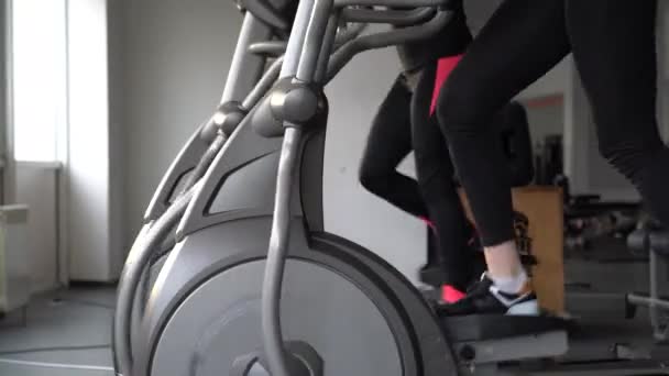 Woman training on stepper or treadmill in fitness club of gym. Side view Power and endurance functional cardio training. Woman health. girl in a fitness club, women on running track Girls on treadmill - Footage, Video