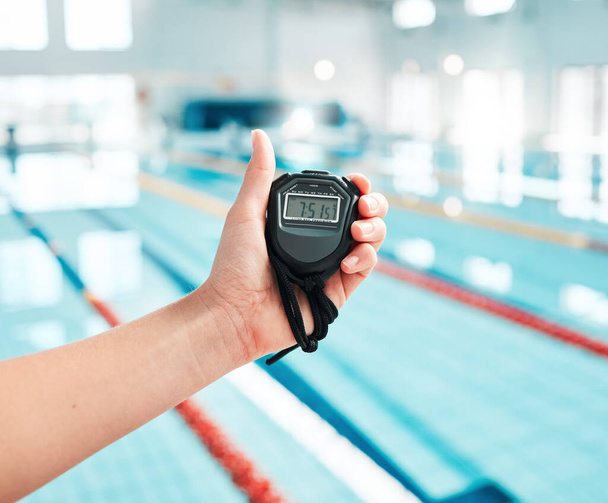 Person, hand and stopwatch by pool in swimming, race or sports training in fitness, exercise or workout. Closeup of swim coach holding timer for monitoring performance, speed or setting challenge. - Photo, Image
