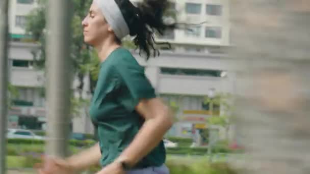 Kenar manzaralı, genç sportif bir kadının sabah koşusu sırasında şehir caddesinde koşarken çekilmiş bir fotoğrafı. - Video, Çekim