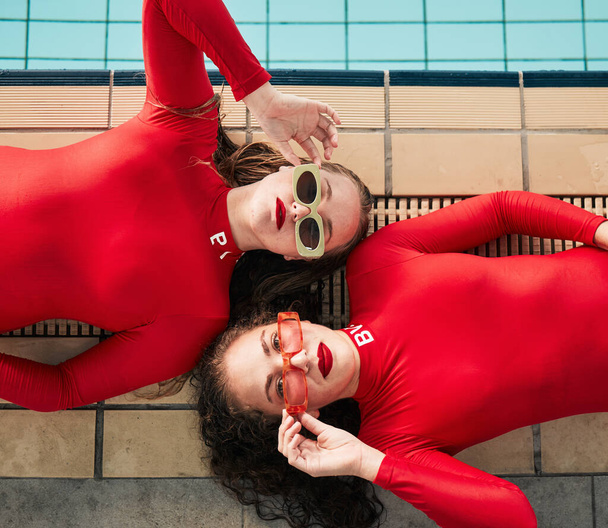 Móda, sluneční brýle a plavky žen v červeném obleku u krytého bazénu. Portrét nad mladými ženami se sportovním stylem, elegancí a uměním nebo luxusem v značkovém oblečení. - Fotografie, Obrázek