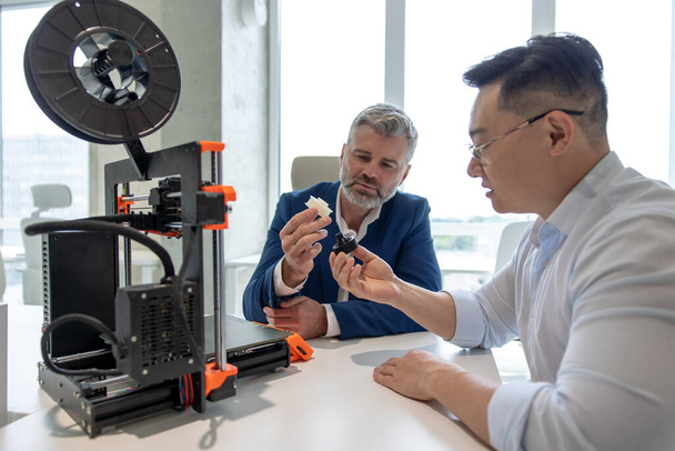 Innovative industrial engineers using 3D printer to build complex component, scientists using high-tech machinery for futuristic design. - Valokuva, kuva