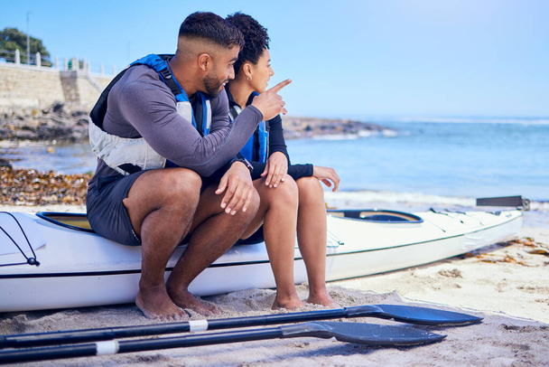 Couple, talking and outdoor for kayak or travel at a beach with a partner for teamwork. A man and woman with a canoe for sports, water adventure and vacation or freedom pointing at space in nature. - Photo, Image
