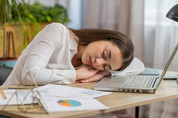 ノートパソコンで働く眠い白人の若いビジネス女性労働者を退屈し、オフィスで眠りに落ちる手にもたれています。疲れ果てたフリーランスの仕事中毒の女の子。雇用、職業、仕事なし - 写真・画像