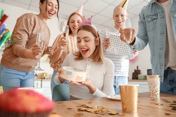 Молодая женщина с тортом на день рождения от своих друзей на вечеринке - Фото, изображение