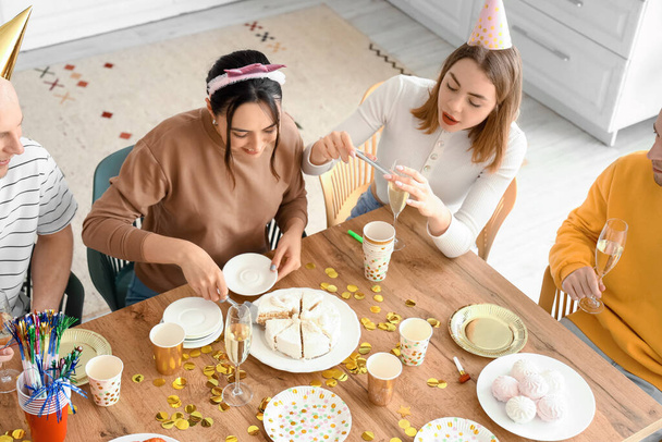 Mujer joven cortando pastel de cumpleaños en la fiesta con sus amigos - Foto, imagen