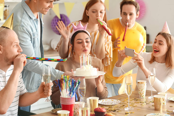 Молодая женщина загадывает желание на дне рождения со своими друзьями - Фото, изображение