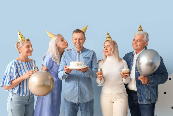 Idős emberek tortával és lufikkal ünneplik a születésnapot kék alapon - Fotó, kép