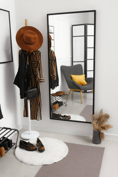 Interieur van lichte hal met spiegel, rek en schoenenstandaard - Foto, afbeelding