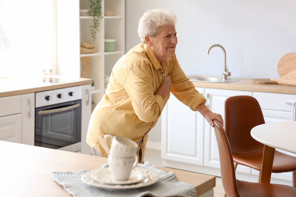 Oudere vrouw heeft een hartaanval in de keuken - Foto, afbeelding