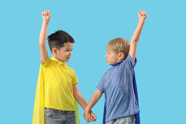 Симпатичные маленькие мальчики в костюмах супергероев на синем фоне - Фото, изображение
