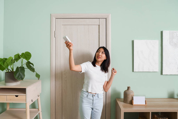 Kaunis aasialainen nainen kytkemällä ilmastointilaite kotona - Valokuva, kuva