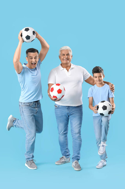 Ragazzino con suo padre e suo nonno in possesso di palloni da calcio su sfondo blu - Foto, immagini