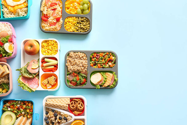 Много обеденных коробок с различными вкусными блюдами на голубом фоне - Фото, изображение