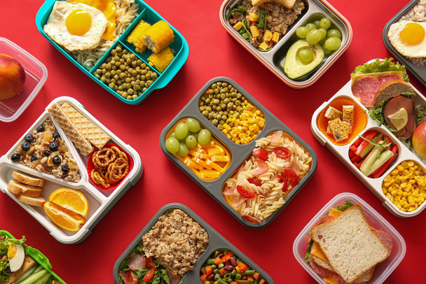 Many lunchboxes with different delicious food on red background - Photo, Image