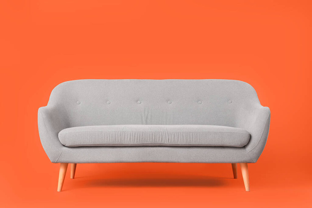 Gemütliches graues Sofa auf rotem Hintergrund - Foto, Bild