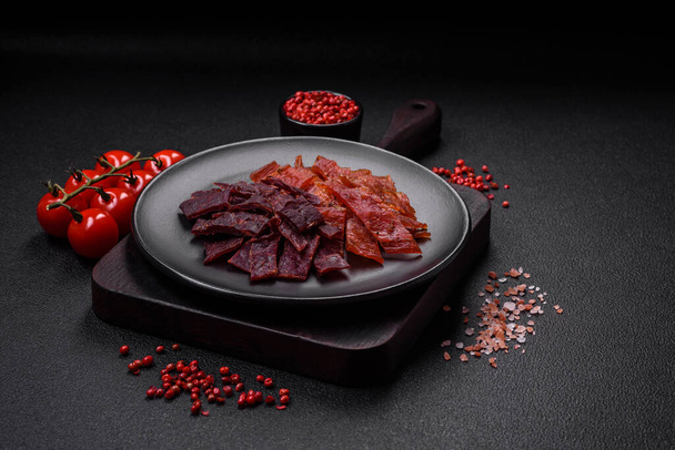 Lahodné sušené telecí nebo krůtí maso se solí, kořením a bylinkami na tmavém betonovém pozadí - Fotografie, Obrázek