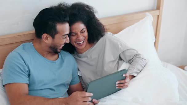 タブレット,映画,そして朝に一緒にベッドでカップルと笑って,自宅でリラックスします. テクノロジー,ソーシャルメディア,またはアパートの寝室でビデオを見ている男女のアプリ. - 映像、動画