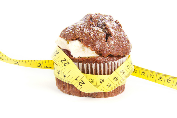 Chocolate muffin with a tape measure around it on white - Zdjęcie, obraz