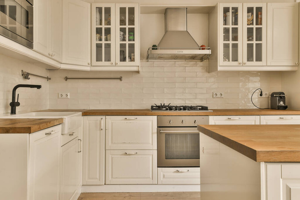 a kitchen with white cupboards and wood counter tops on the island in front of the sink is wooden top - Photo, Image