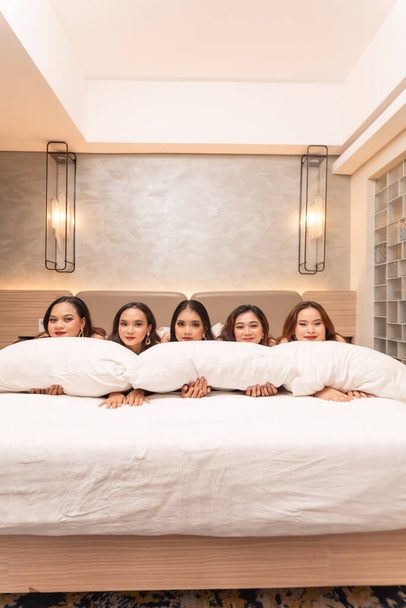 група азіатських жінок спить і спить на білих подушках зі своїми друзями в розкішному готелі вночі - Фото, зображення