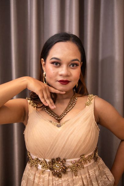 an Asian woman is posing beautifully while wearing makeup and an elegant party dress at a hotel at night - Zdjęcie, obraz